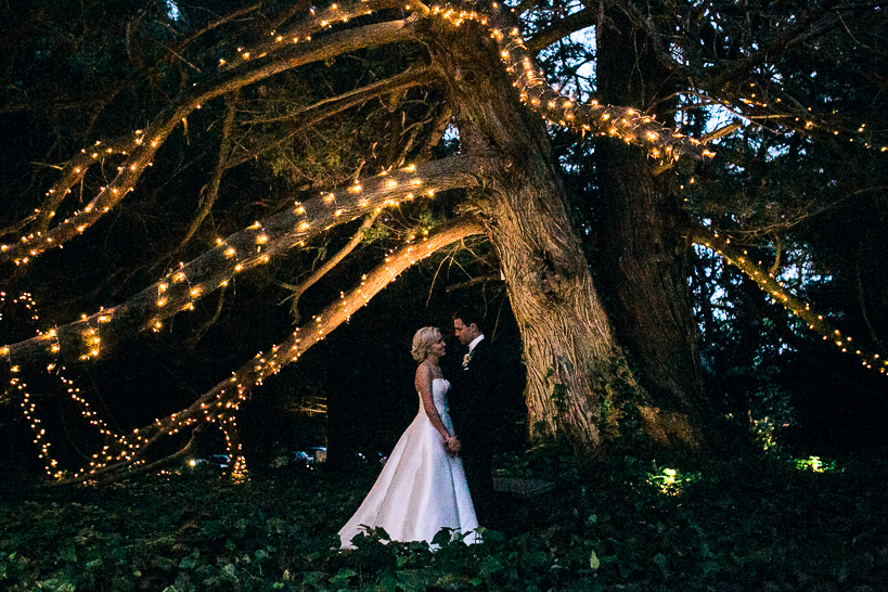 Couple Shot unter großem Baum mit Lichterkette