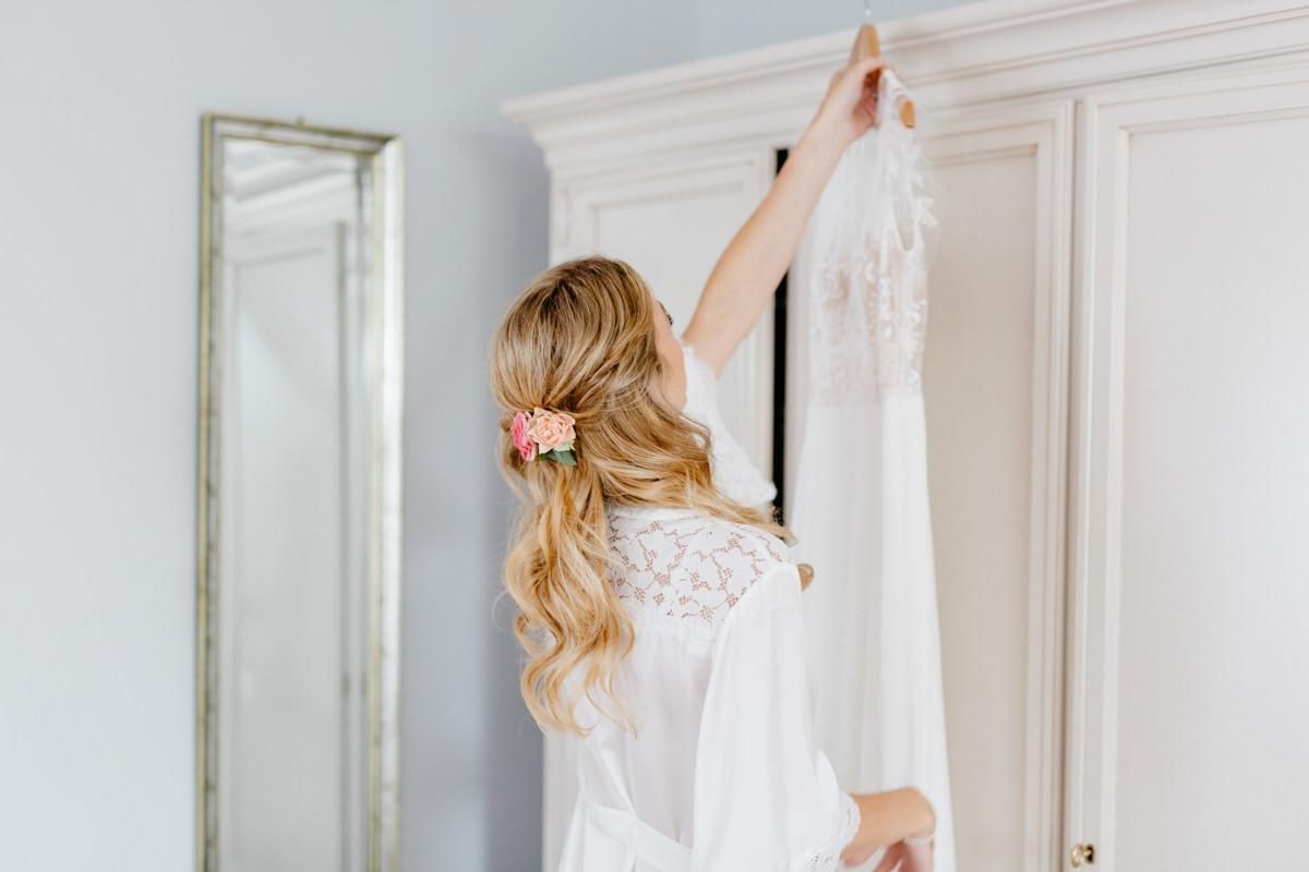 Braut-greift-nach-Hochzeitskleid-mit-schöner-Frisur