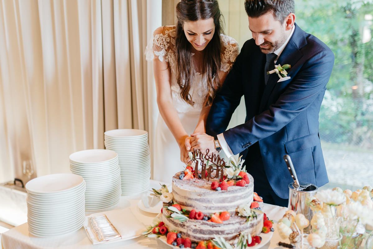 Brautpaar befolgt Hochzeitstradition und schneidet die Torte gemeinsam an
