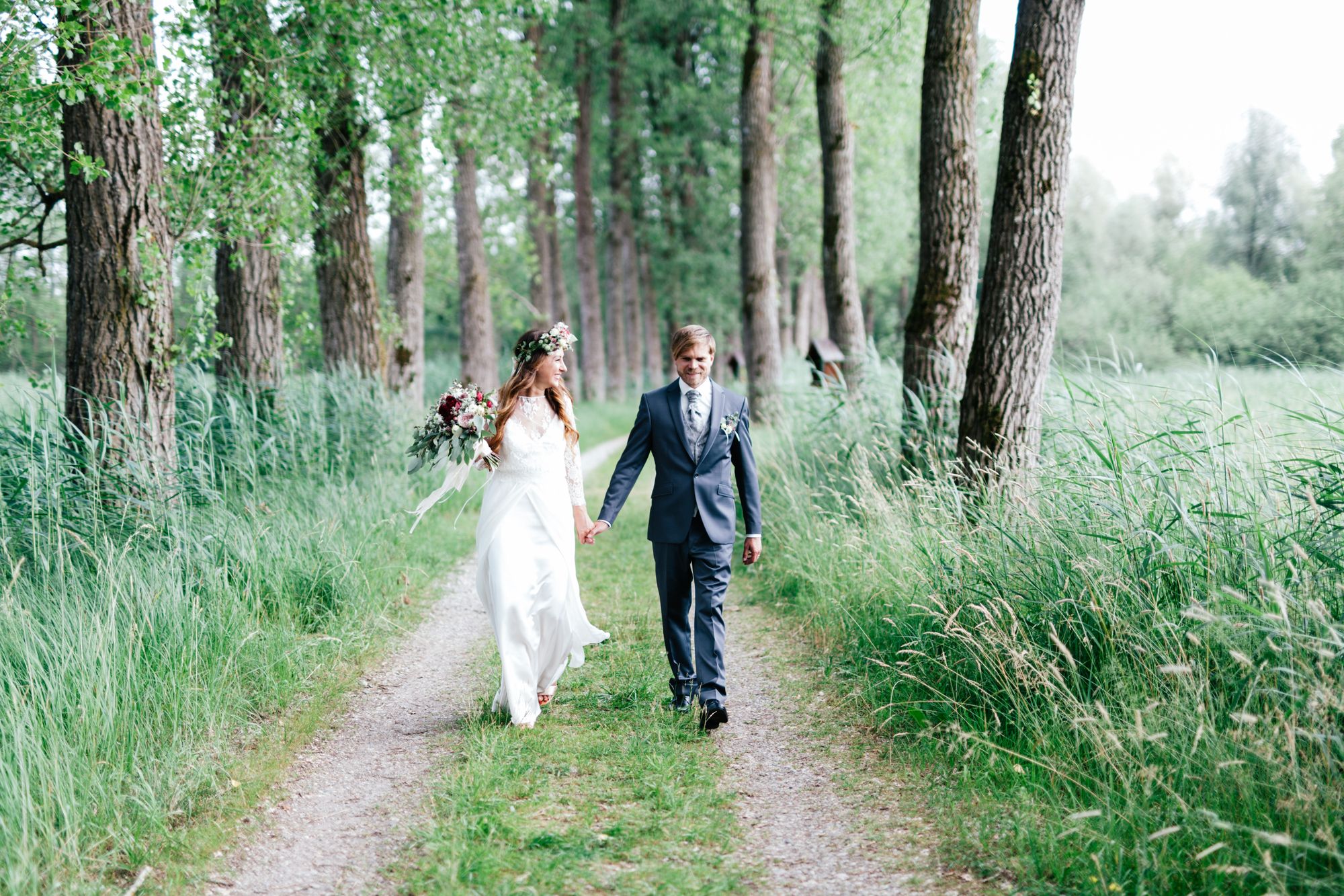 Brautpaar läuft Hand in Hand durch den Wald