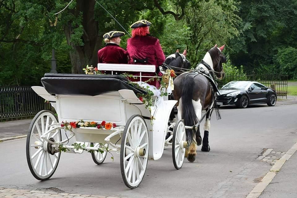 Eine weiße Hochzeitskutsche fährt auf der Straße