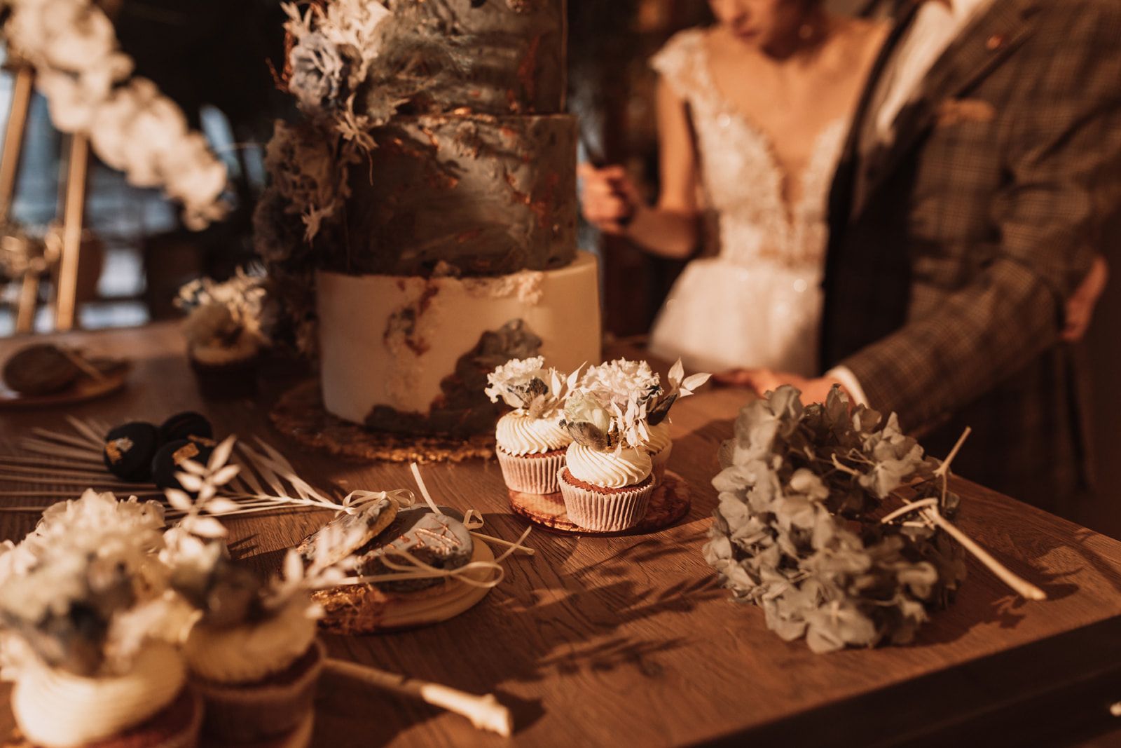 Cupcakes stehen vor der grauen Hochzeitstorte