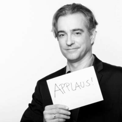 Der Redenschreiber hält ein Schilf mit "Applaus" hoch
