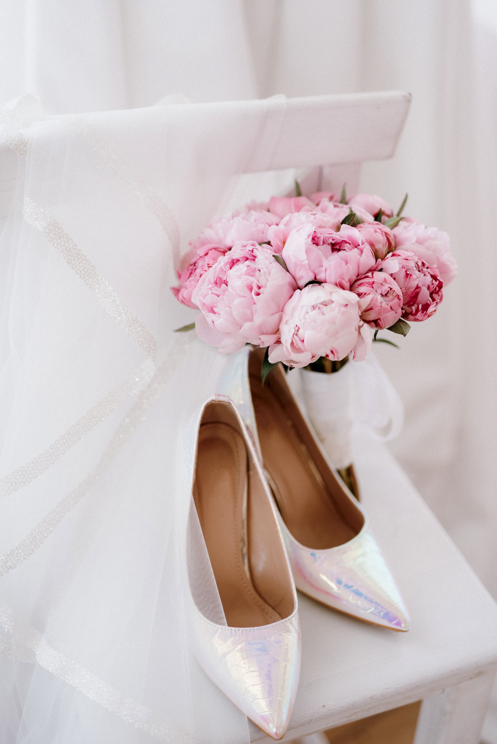 Glitzerne Brautschuhe liegen auf einem Stuhl