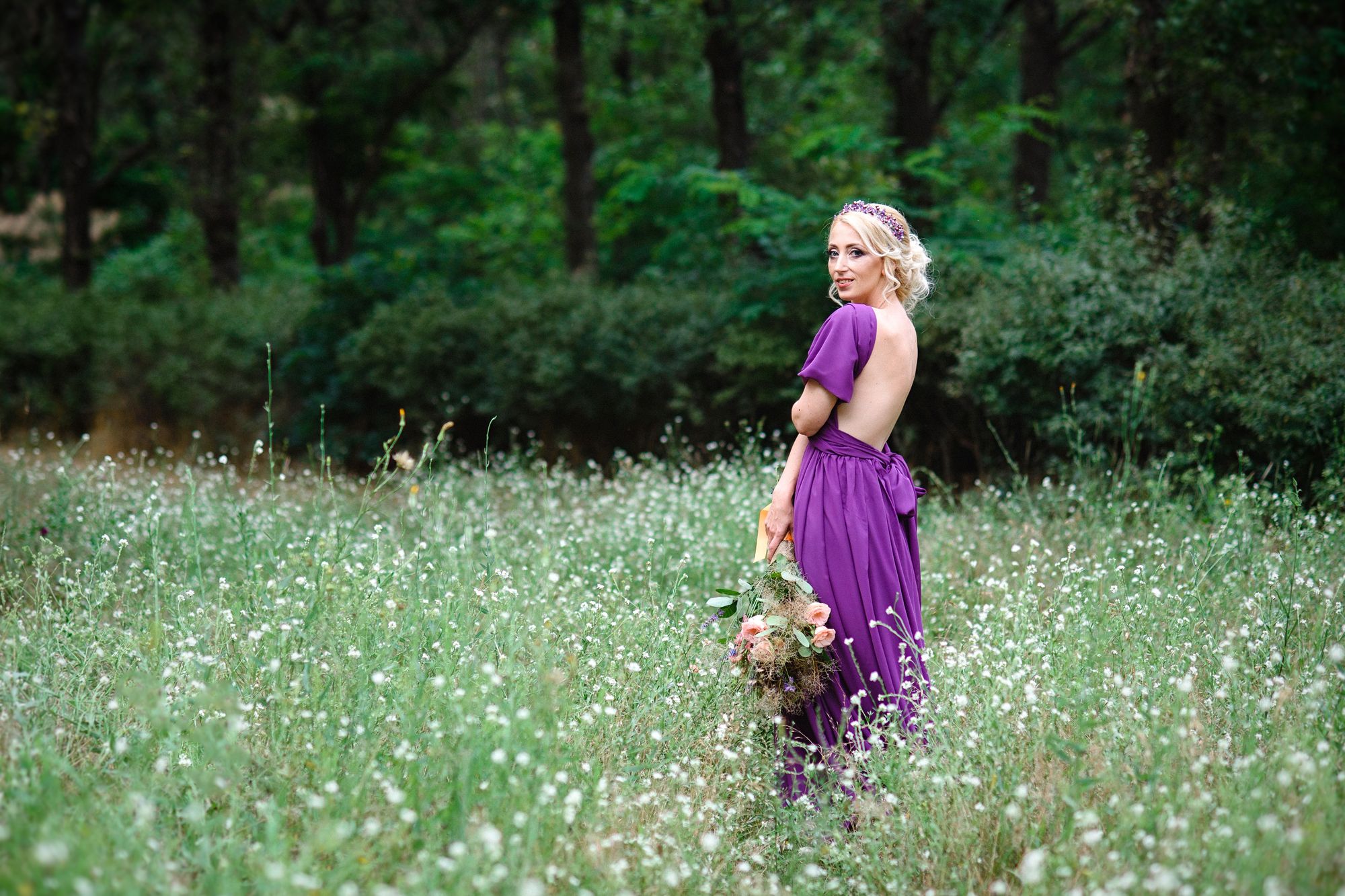 Braut mit lila Brautkleid in der Wiese