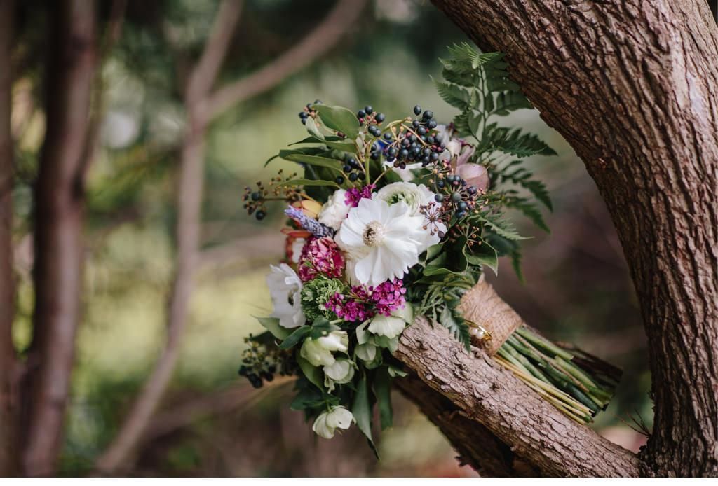 grüner Brautstrauß mit Bunten Blumen in Baum fotografiert