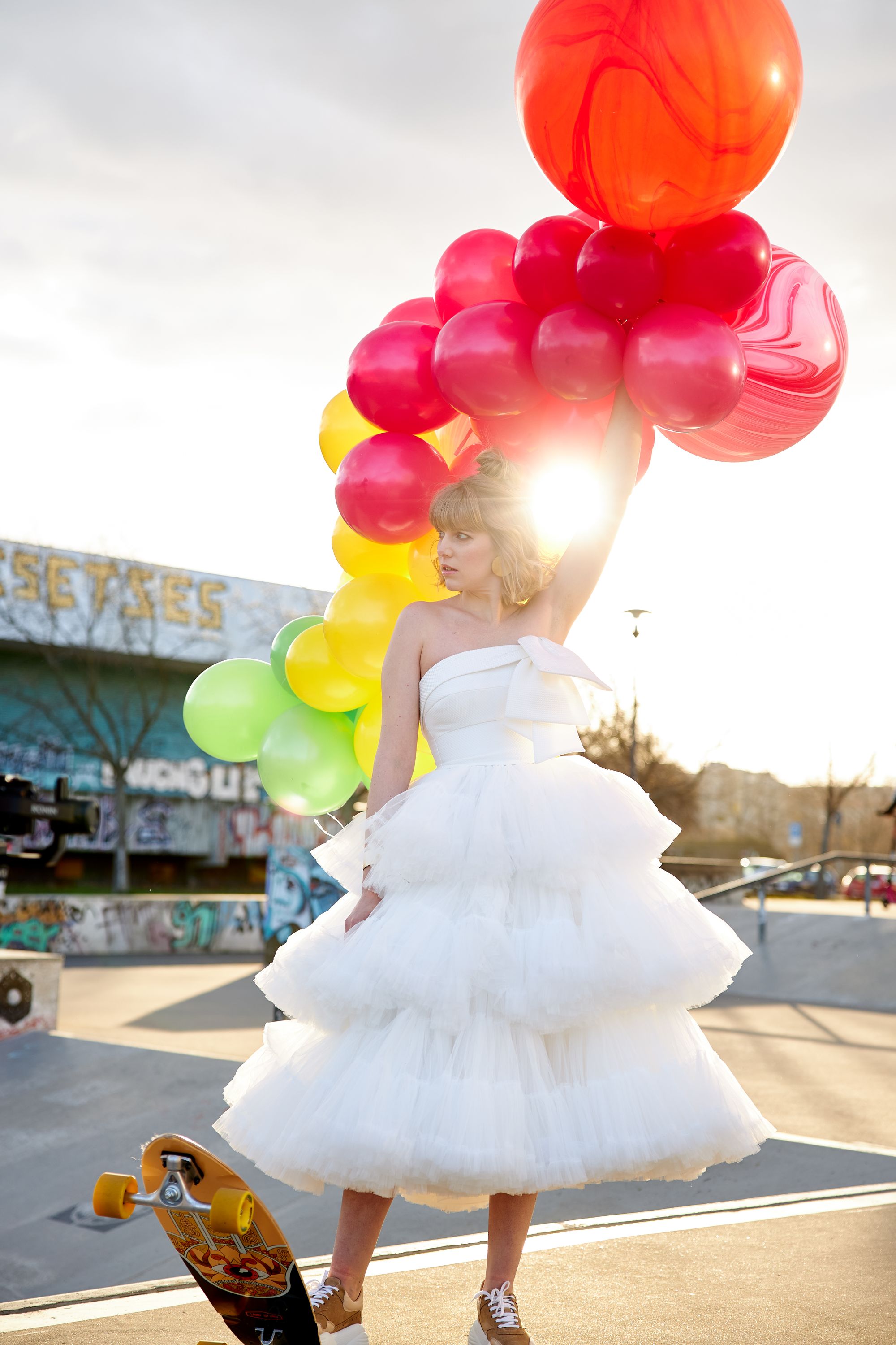 Braut posiert in Skaterpark mit Luftballons und Skateboard