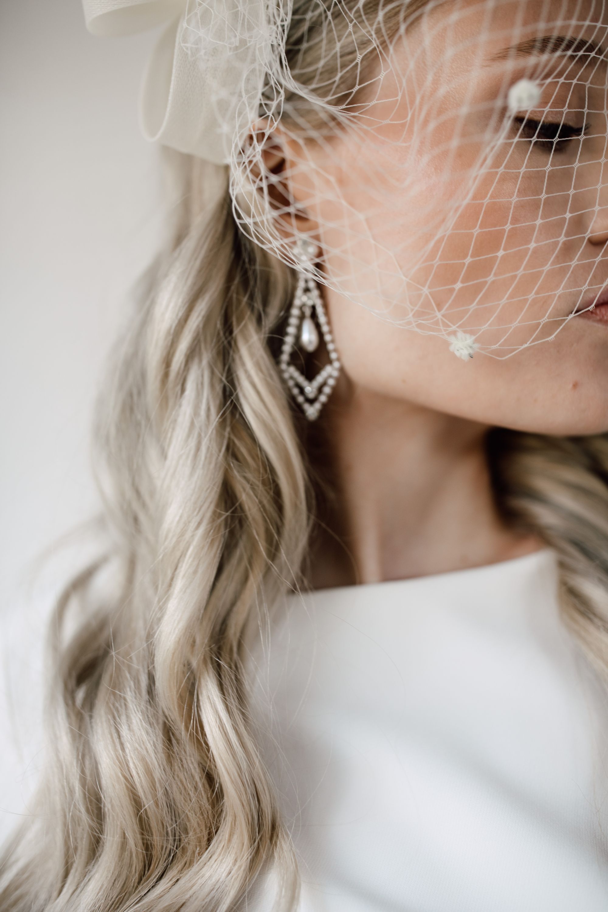Nahaufnahme Braut mit Fascinator und großen Ohrringen