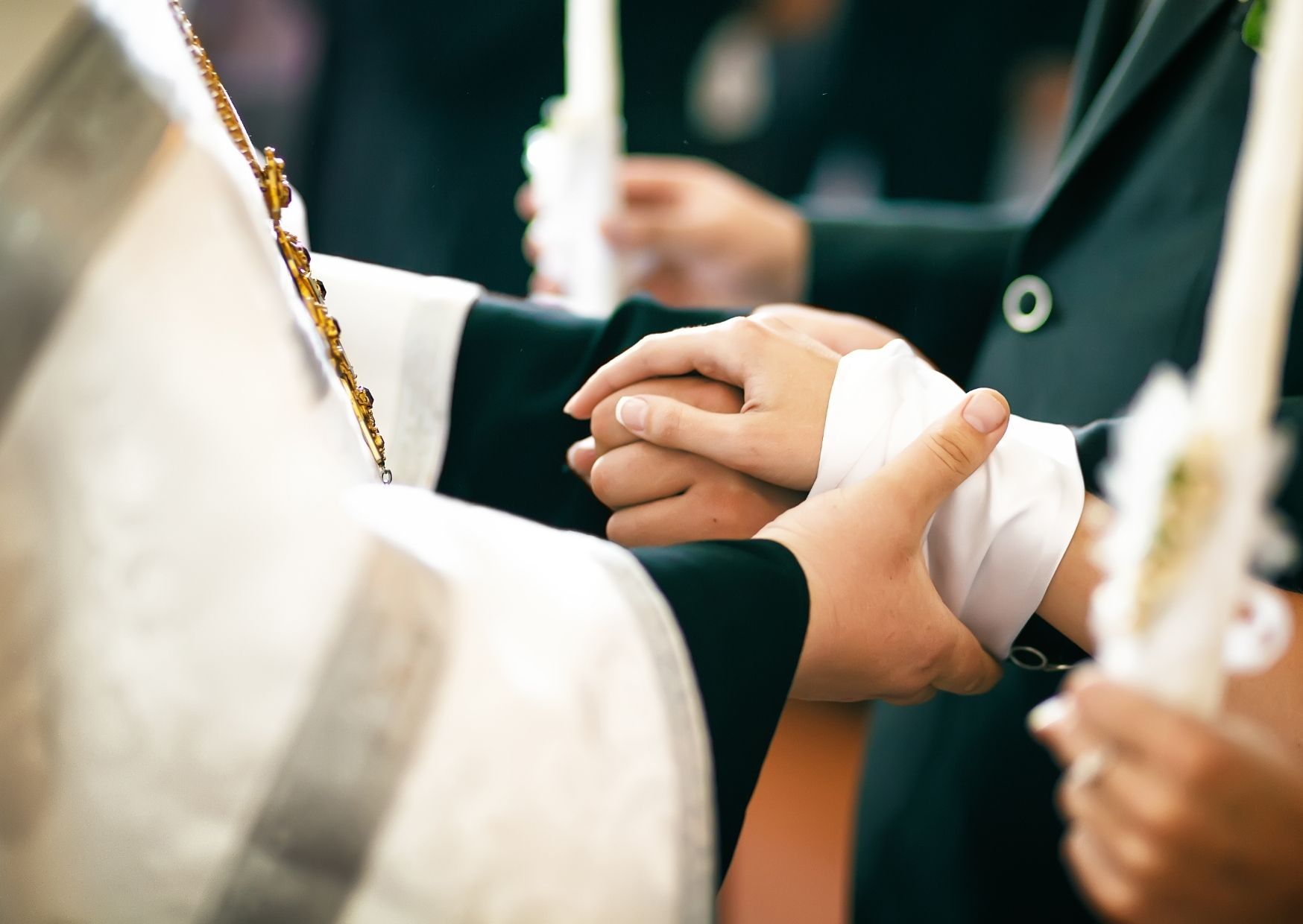 kirchlich heiraten - Pfarrer hält die Hände des Brautpaars während der hochzeit