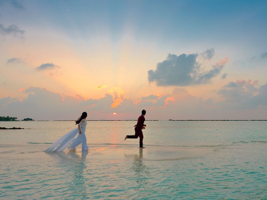 Paar läuft beim Sonnenuntergang auf einer Sandbank im Meer