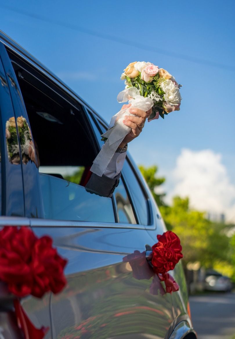 Brautpaar hält Brautstrauß aus dem Hochzeitsauto