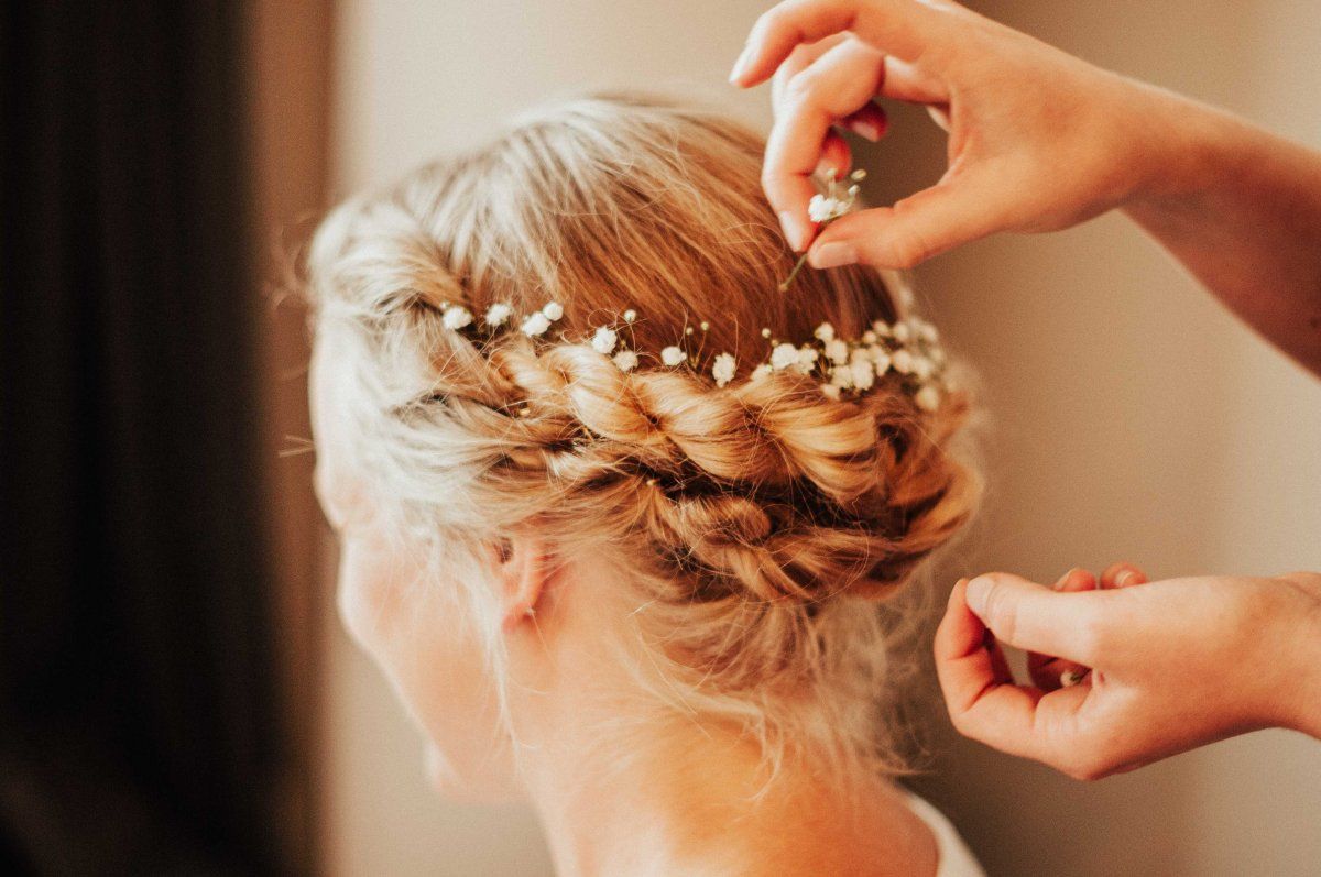 Der Braut wird eine Haarnadel in die aufwendige Frisur gesteckt.