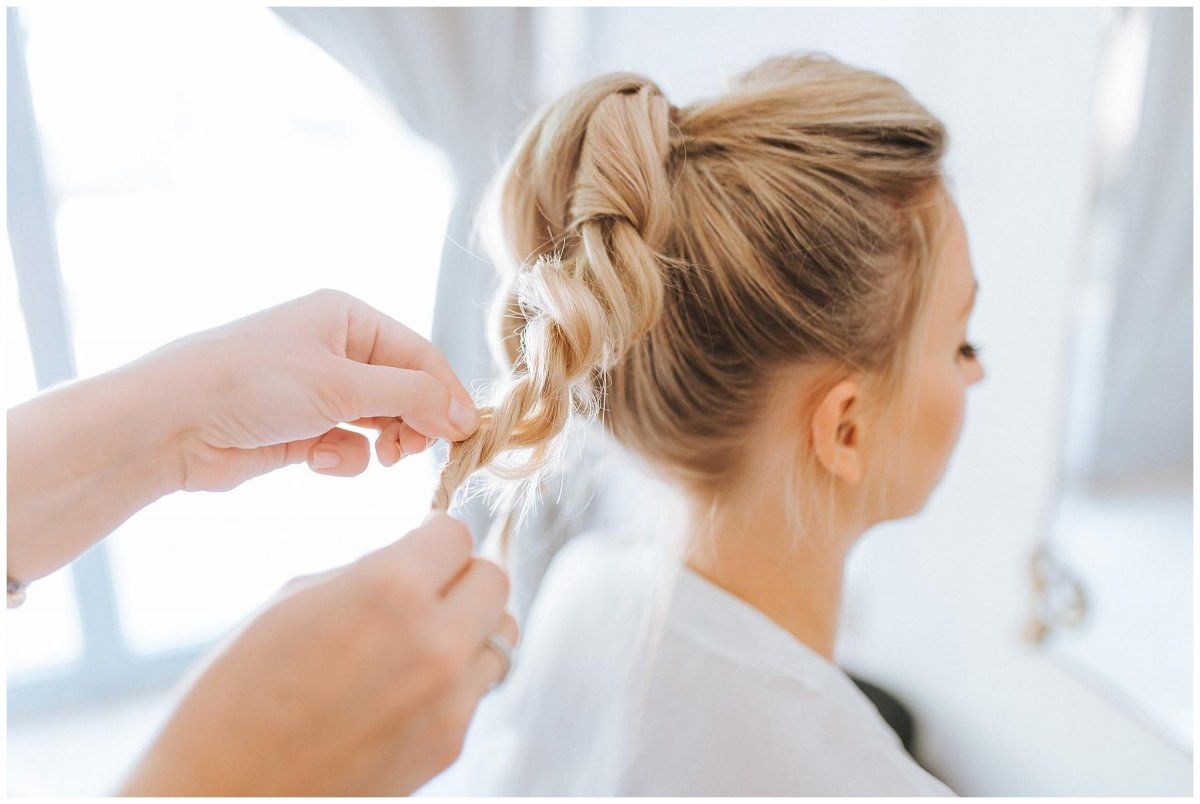 Die Braut sitzt vor einem Spiegel beim Friseur.