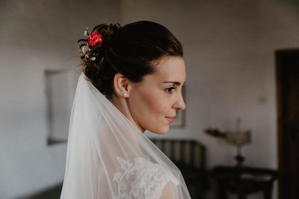 Die Braut trägt hochgesteckte Haare und dazu einen Schleier.