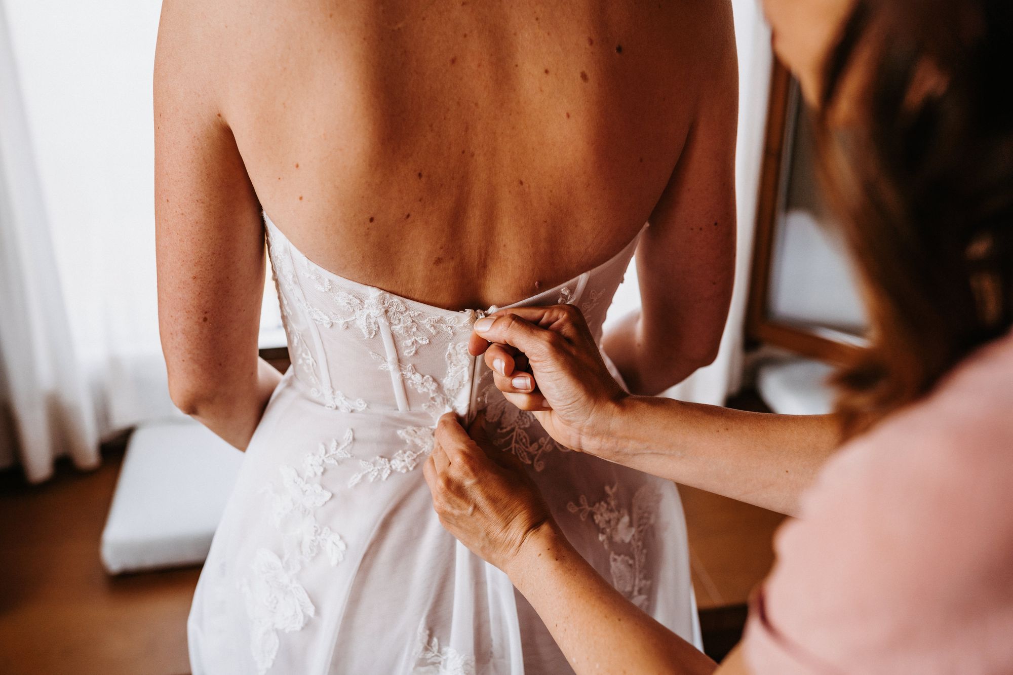 Das Kleid der Braut wird geschlossen.