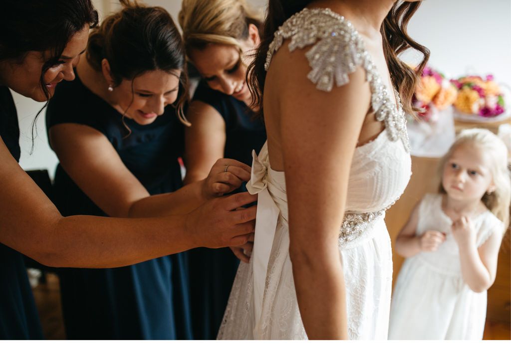 Die Brautjungfern helfen der Braut beim Anziehen des Brautkleides.