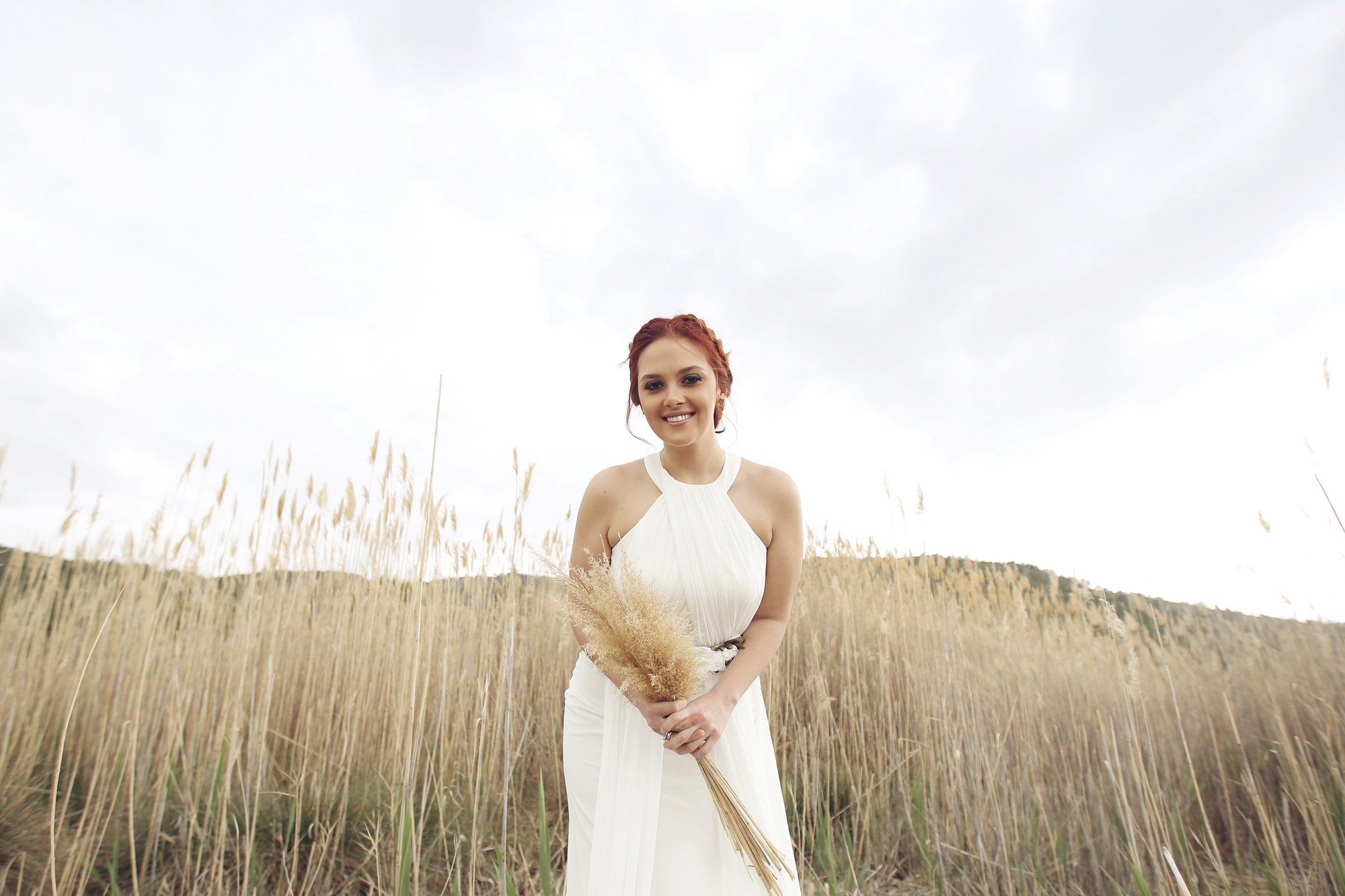 Die Braut trägt ein Neckholder Brautkleid und dazu eine Hochsteckfrisur.